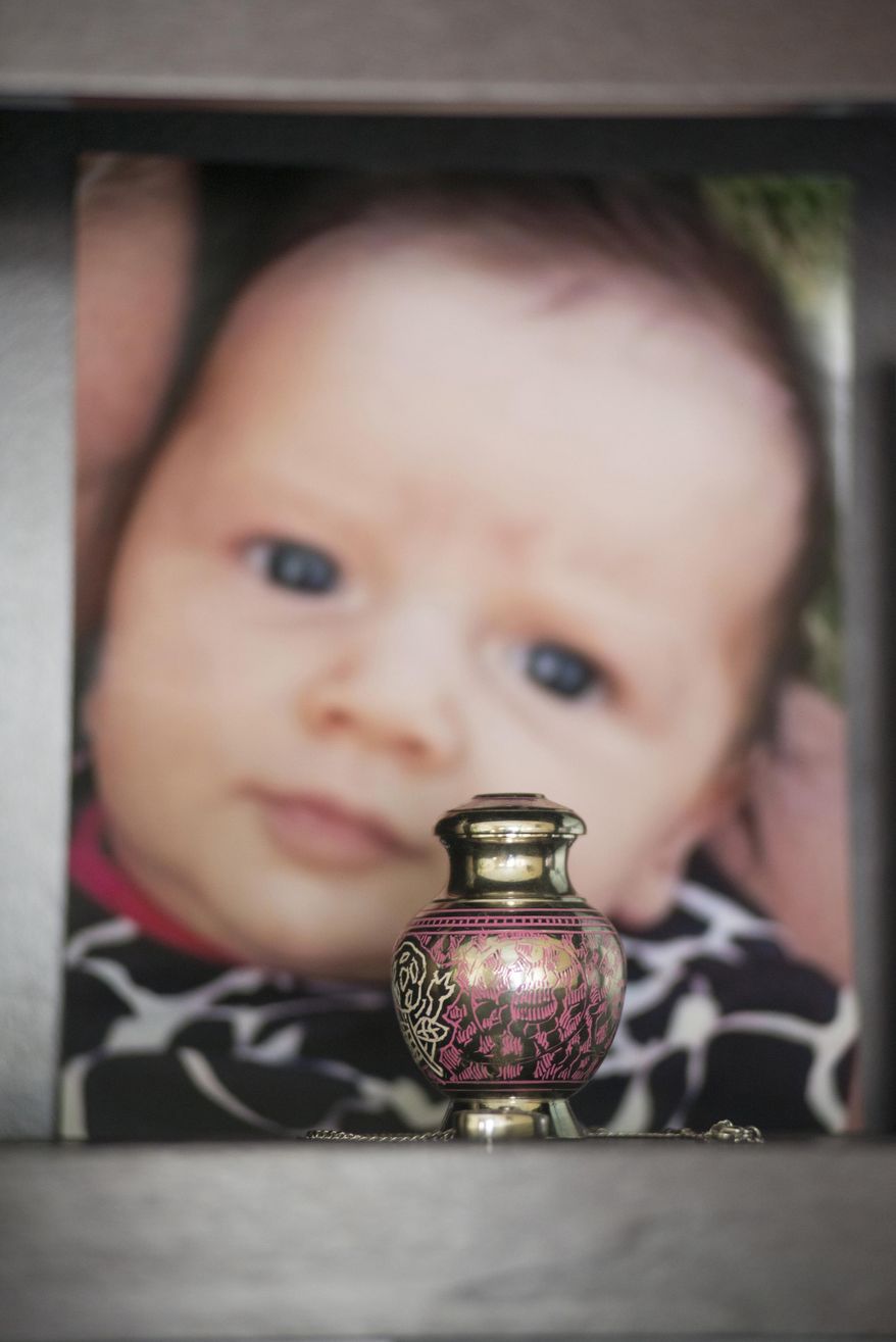 ADVANCE FOR USE THURSDAY, DEC. 18, 2014, AT 12:01 A.M. EST AND THEREAFTER- In this Nov. 13, 2014, photo, a small urn containing the ashes of Mattisyn Blaz is displayed on a bookshelf in front of a photo of the infant girl in the home of Jennifer Blaz, 34, in Butte, Mont. At least 760 children died of abuse or neglect in the U.S. in a six-year span in plain view of child protection authorities, The Associated Press has found, including the death of 2-month-old Mattisyn. (AP Photo/Lido Vizzutti)