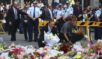 Australian Prime Minister Tony Abbott and his wife Margie pay their respect to the victims of the siege in Martin Place in Sydney central business district, Australia. Tuesday, Dec. 16, 2014. Abbott has laid flowers at a makeshift memorial in Sydney for the victims of a central city cafe siege which left three people dead. (Photo: Steve Christo)