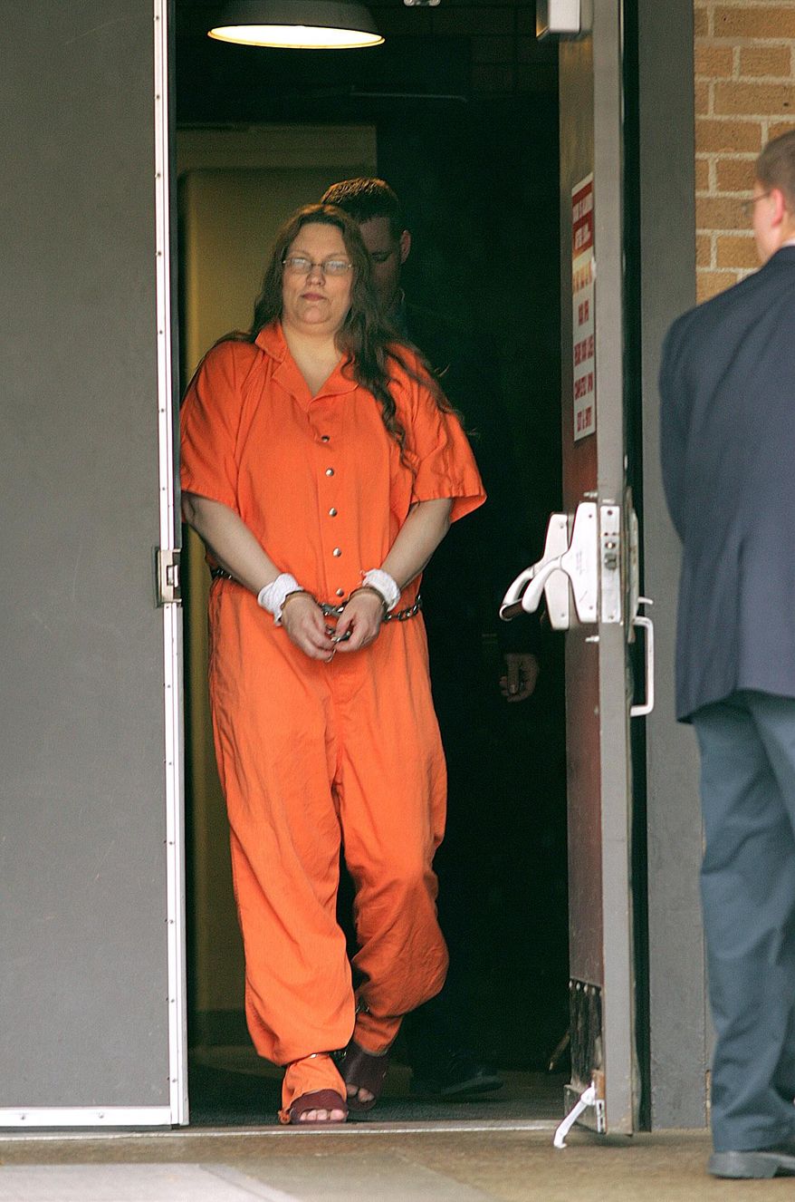 FILE - In this April 12, 2005 file photo Angela Johnson is escorted from the Federal Courthouse in Sioux City, Iowa. Federal prosecutors are giving up their long pursuit of the death penalty against Johnson who was convicted of helping kill five people in 1993. The government said in a court filing Wednesday, Dec. 17, 2014, that it will no longer seek to execute Johnson. Johnson is expected to be sentenced to life in prison without parole. (AP Photo/Sioux City Journal, Jerry Mennenga, File)
