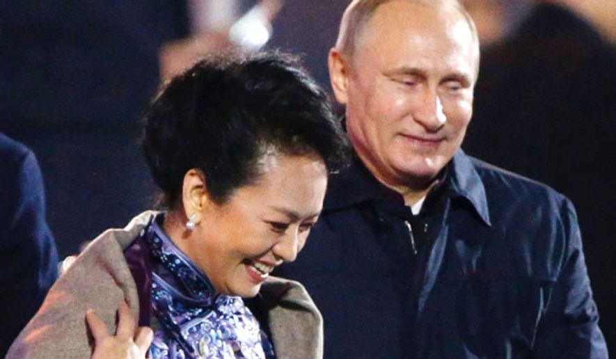 Russia&#x27;s President Vladimir Putin, right, puts a shawl on Peng Liyuan, the wife of Chinese President Xi Jinping, at the Asia-Pacific Economic Cooperation (APEC) summit in Beijing, Nov. 10, 2014. (Associated Press) ** FILE **