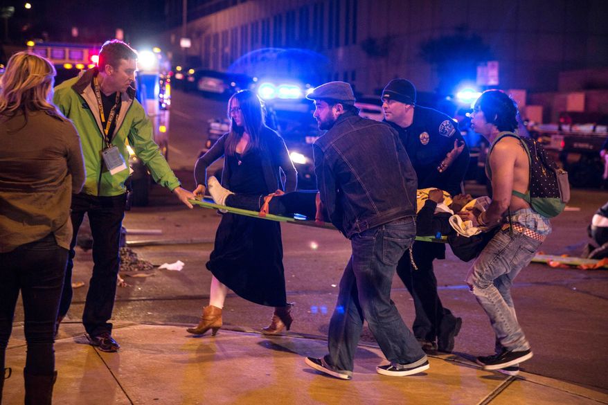 Bystanders assist first responders at the scene at SXSW festival in Austin, Texas, where 2 people died and dozens more were injured after a hit and run. Amos Guiora, a law professor at the University of Utah is leading a push to impose a duty on bystanders to take affirmative action to assist those they see in peril. (AP Photo/Colin Kerrigan, File)