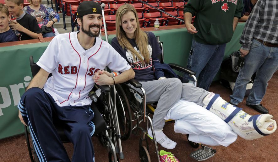 FILE - In this May 23, 2013 file photo, Boston Marathon bombing survivor Pete DiMartino, of Rochester, N.Y., and his girlfriend, Rebekah Gregory, hold hands prior to DiMartino throwing out the ceremonial first pitch before a Red Sox game at Fenway Park in Boston. DiMartino and Gregory were injured in an explosion near the finish line of the Boston Marathon. The couple were chosen for the “Dream Wedding Contest” given by Theknot.com, a wedding planning website. Gregory’s fit-and-flare Sophia Moncelli dress, the couple’s rings and location were chosen by the site’s users. The couple tied the knot last April in front of 125 people at the Biltmore Estate in Asheville, North Carolina. Her search for the perfect wedding dress is featured in Friday night’s season finale of TLC’s popular reality show, “Say Yes to the Dress.” (AP Photo/Charles Krupa, File)