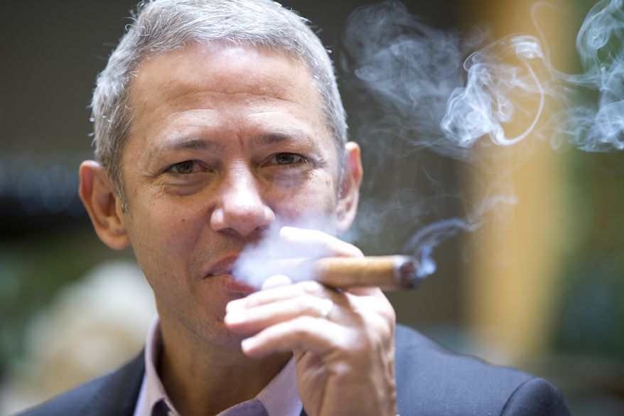 In this Thursday, Dec. 18, 2014 photo, Roberto Ramos, president of the Cubaocho Art and Research Center in Miami’s Little Havana neighborhood, smokes a cigar in the court yard of the center. The Cuban cigar is set to make its first legal appearance in the United States in years, with relaxed guidelines allowing travelers to return with a few of the once-forbidden items in their suitcases. But the cigars won’t roll into stores just yet, and owners say they aren’t worried about business. (AP Photo/Wilfredo Lee)