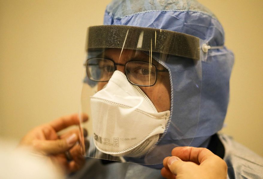 FILE - In this Tuesday, Oct. 28, 2014 file photo, Allina paramedic Jake Shepard gets help putting on a face shield as Allina EMS first responders receive training on the latest protocol for handling future patients possibly infected with Ebola in Mounds View, Minn. The Ebola outbreak in West Africa hit home in Minnesota, which shelters one of the largest Liberian communities in the U.S. Health officials began monitoring travelers returning from the affected countries this fall and four Minnesota hospitals became designated treatment centers. (AP Photo/The Star Tribune, David Joles, File)