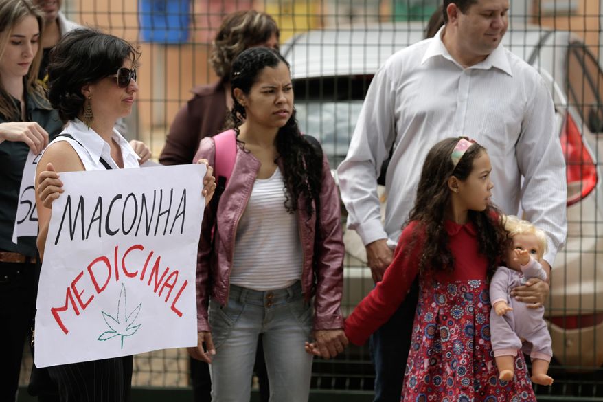 Relatives and friends of patients protest for the legalization of cannabidiol, a marijuana derivative that's banned in Brazil, outside the Health Surveillance Agency (ANVISA) in Brasilia, Brazil, Thursday, Dec. 18, 2014. The Brazilian government says it will study next month the possibility of legalizing the use of the marijuana derivative to treat people suffering from severe seizures. (AP Photo/Eraldo Peres)