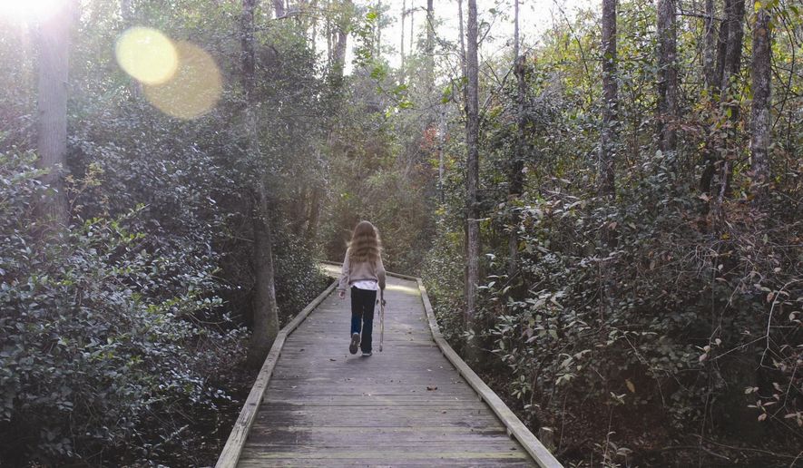 Zsa Zsa White walks down the wooden walkway through Woods Bay Park in Olanta, S.C. during a recent trip with her family. (AP Photo/Morning News, Melissa Rollins)