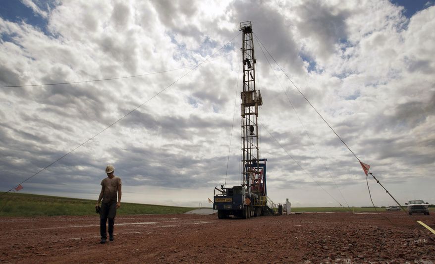 In this Tuesday, July 26, 2011 file photo, a worker walks by an oil derrick outside of Williston, N.D. Relief could be on the horizon for strapped public services in the Northern Plains' booming oil patch, as elected leaders in Montana and North Dakota move to steer more money into the region during the states' upcoming legislative sessions. (AP Photo/Gregory Bull, File)