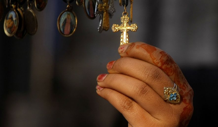 A Pakistani Christian girl buys a cross at a shop outside a local church on Christmas Day in Peshawar, Pakistan, Thursday, Dec. 25, 2014. (AP Photo/Mohammad Sajjad)