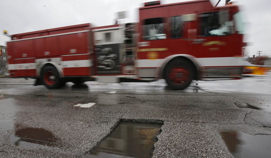 In this Dec. 16, 2014 photo, a fire engine truck rolls past potholes filled with rainwater in East Cleveland, Ohio. (AP Photo/Tony Dejak)