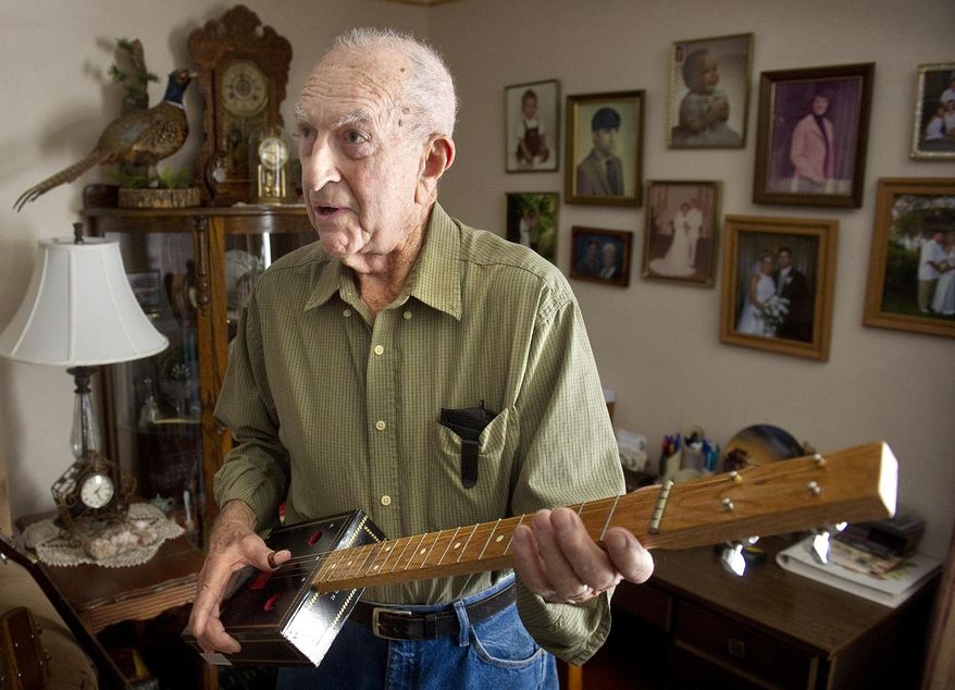HOLD FOR RELEASE UNTIL 12:01 A.M. CST. In this photo taken on Dec. 19, 2014, Levoy Saltzman plays an early version of the cigar box guitars he makes in his Shickley, Neb. garage. (AP Photo/The Journal-Star, Eric Gregory ) LOCAL TELEVISION OUT; KOLN-TV OUT; KGIN-TV OUT; KLKN-TV OUT