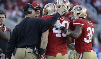 San Francisco 49ers fullback Bruce Miller, center, is congratulated by head coach Jim Harbaugh, left, and running back Alfonso Smith (38) after scoring on a 3-yard touchdown reception against the Arizona Cardinals during the third quarter of an NFL football game in Santa Clara, Calif., Sunday, Dec. 28, 2014. (AP Photo/Marcio Jose Sanchez)