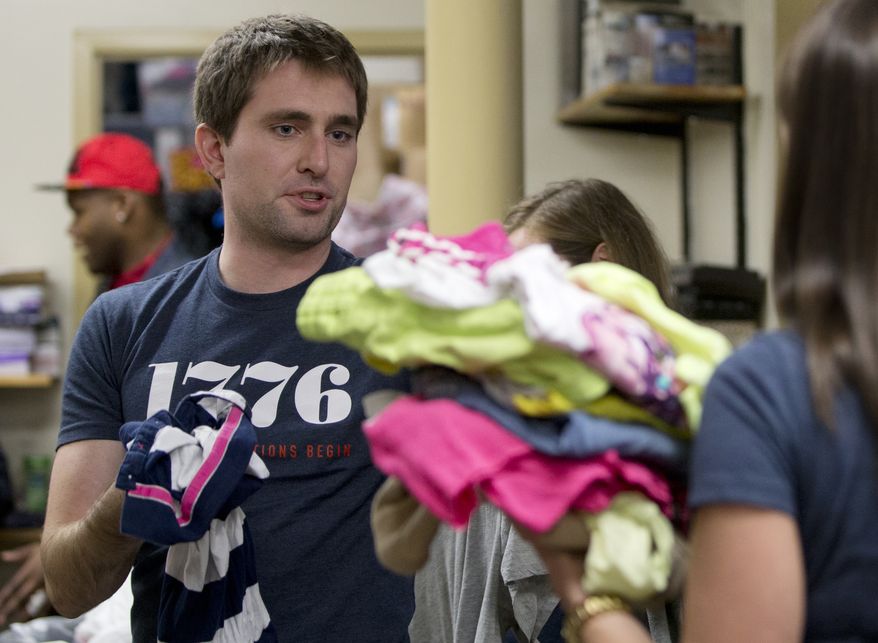 This, Dec. 16, 2014, photo shows Patrick McAnaney, from the company 1776, as he volunteers in the clothing room with a group of his coworkers at Bread for the City in Washington. Tired of hearing people grouse about a tuned-out, apathetic younger generation? Well, here’s a comeback: Today’s young Americans are serious when it comes to volunteering. In fact, measured against their parents as young adults back in the 1980s, those under 30 today are more likely to say that citizens have a “very important obligation” to give their time, an Associated Press-GfK poll finds. (AP Photo/Carolyn Kaster)