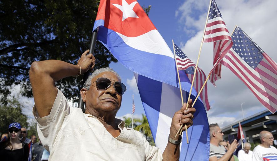 Evilio Ordonez holds Cuban and American flags during a protest against President Barack Obama&#x27;s plan to normalize relations with Cuba, Saturday, Dec, 20, 2014, in the Little Havana neighborhood of Miami. Florida newspaper editors voted President Barack Obama’s mid-December move to normalize relations with Cuba as one of the top stories of the year. (AP Photo/Lynne Sladky)