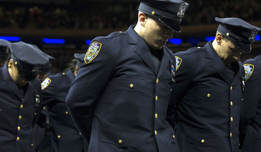 New recruits bow their heads for a moment of silence for deceased officers Rafael Ramos and Wenjian Liu during a New York Police Academy graduation ceremony, Monday Dec. 29, 2014, at Madison Square Garden in New York. Nearly 1000 officers were sworn in as tensions between city hall and the NYPD continued following the Dec. 20 shooting deaths of officers Ramos and Liu. (AP Photo/John Minchillo)
