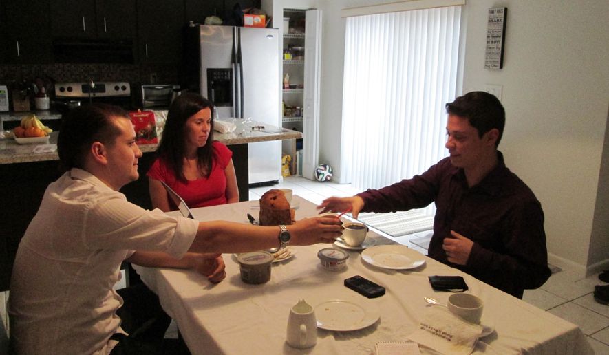 Isabel Rodriguez, left, hands coffee to his husband, Felipe Sousa-Rodriguez, right, at the Davie, Fla. home of Felipe’s sister. The two are longtime immigrant and LGBTQ activists who walked from Miami to Washington, in 2010, to call attention to the struggles of youths living in the United States illegally. (AP Photo)