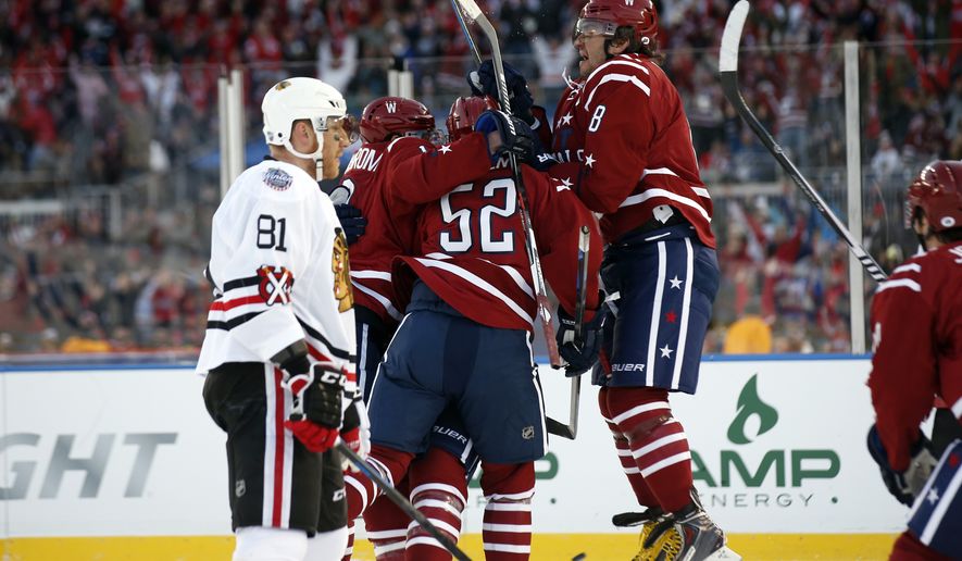 Washington Capitals center Nicklas Backstrom (19), from Sweden, defenseman Mike Green (52) and left wing Alex Ovechkin (8), from Russia, surround right wing Troy Brouwer (20) after Brouwer scored the winning goal as Chicago Blackhawks right wing Marian Hossa (81), from Slovakia, looks on in the third period of the Winter Classic outdoor NHL hockey game at Nationals Park, Thursday, Jan. 1, 2015, in Washington. The Capitals won 3-2. (AP Photo/Alex Brandon)