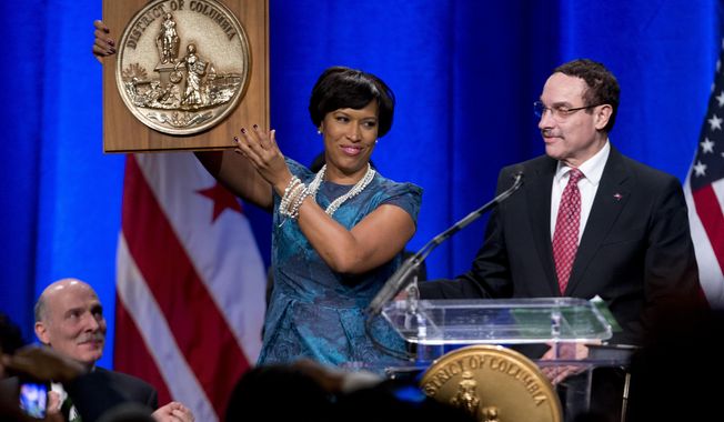 Washington Mayor Muriel Bowser holds the seal of the District of Columbia after accepting it from former Mayor Vincent Gray, right, as council chairman Phil Mendelson watches at left, during the District of Columbia Mayoral Inauguration ceremony at the Convention Center in Washington, Friday, Jan. 2, 2015. (AP Photo/Carolyn Kaster)