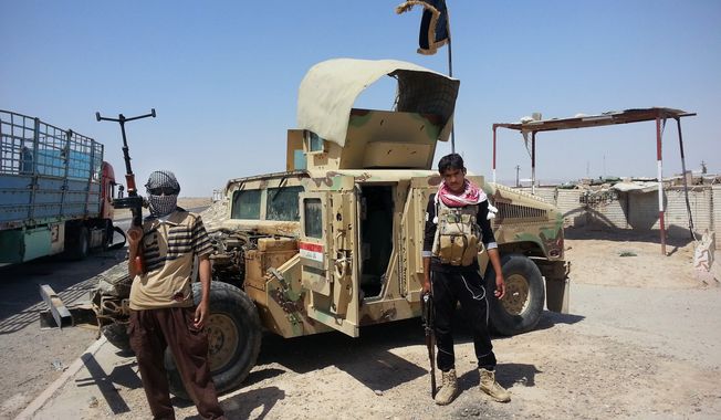 In this file photo taken Thursday, June 19, 2014, Islamic State group militants stand with a captured Iraqi army Humvee at a checkpoint outside Beiji refinery, some 250 kilometers (155 miles) north of Baghdad, Iraq. (AP Photo, File)
