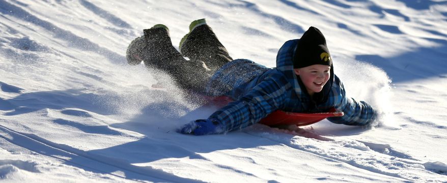 In this Dec. 11, 2013, file photo Zoe Reisen,10, of Dubuque, Iowa, sleds down a hill at Allison-Henderson Park on in Dubuque, Iowa. Faced with the potential bills from people who are injured sledding, Dubuque is one of the cities across the country the is opting to close hills rather than face the risk of large liability claims. (AP Photo/The Telegraph Herald, Jessica Reilly, File)