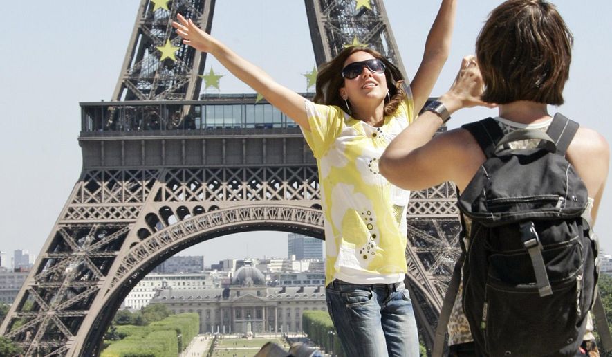 Tourists take pictures in front of the Eiffel Tower in Paris. A strong U.S. dollar is making world travel cheaper for Americans in 2015. (AP Photo/Francois Mori, File)