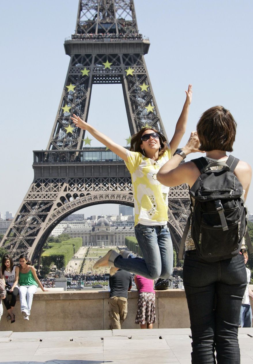 Tourists take pictures in front of the Eiffel Tower in Paris. A strong U.S. dollar is making world travel cheaper for Americans in 2015. (AP Photo/Francois Mori, File)