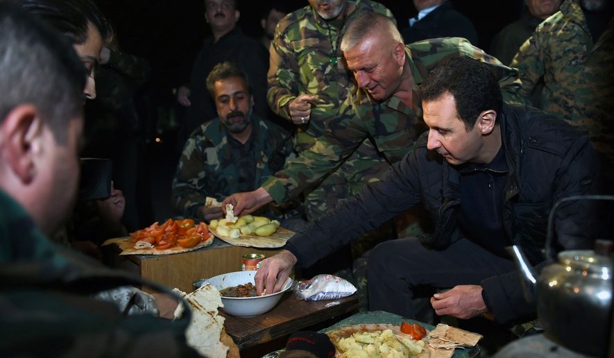 In this Wednesday, Dec. 31, 2014 photo released by the Syrian official news agency SANA, Syrian President Bashar Assad, right, shares a meal with Syrian troops during his visit on the front line in the eastern Damascus district of Jobar, Syria. Assad has made a rare visit to the front line of his country&#39;s civil war, spending New Year&#39;s Eve with his troops in a tense eastern Damascus neighborhood. (AP Photo/SANA)