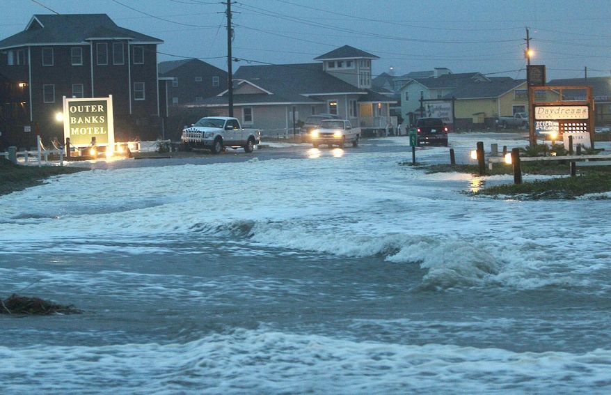 FILE-In this Sunday, Oct. 28, 2012 file photo, Ocean water rolls over NC 12 at the north end of Buxton, N.C. at dawn. A claim that blames the state Transportation Department for flooding that occurs along N.C. Highway 12 in Buxton on Hatteras Island is to get a hearing Wednesday, Jan 7, 2015. (AP Photo/The Virginian-Pilot, Steve Earley, File)