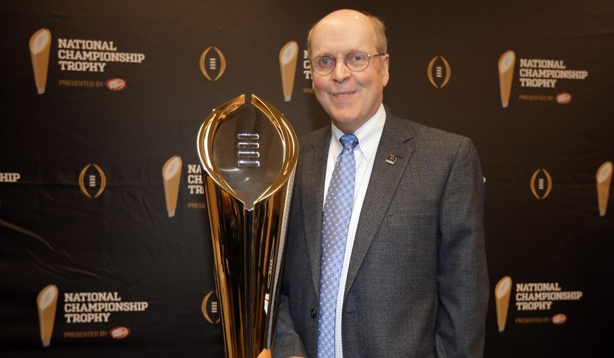 FILE - In this July 14, 2014, file photo, College Football Playoff Executive Director Bill Hancock poses with the College Football Playoff National Championship Trophy in Irving, Texas.The College Football Playoff is a blank slate and those who created it have tried to steer clear of clutter in the hope of creating the next ubiquitous sports brand. (AP Photo/Tony Gutierrez, File)
