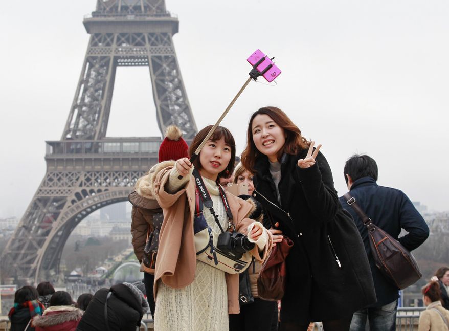Tourists use a selfie stick on the Trocadero Square, with the Eiffel Tower in background, in Paris, Tuesday, Jan. 6, 2015. Selfie sticks have become enormously popular among tourists because you don’t have to ask strangers to take your picture, and unlike hand-held selfies, you can capture a wider view without showing your arm. But some people find selfie sticks obnoxious, arguing that they detract from the travel experience. (AP Photo/Remy de la Mauviniere)