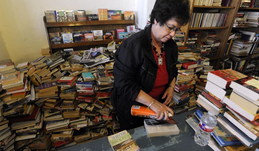 Martha Jarred cleans a paperback book cover with furniture polish Dec. 12, 2014, at Henderson Book Store in Haskell. Jarred tries to clean each book that comes in the used book store. (AP Photo/The Abilene Reporter-News, Ronald W. Erdrich)