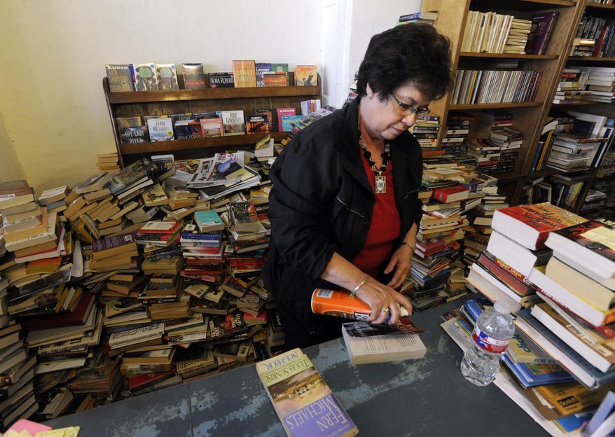 Martha Jarred cleans a paperback book cover with furniture polish Dec. 12, 2014, at Henderson Book Store in Haskell. Jarred tries to clean each book that comes in the used book store. (AP Photo/The Abilene Reporter-News, Ronald W. Erdrich)