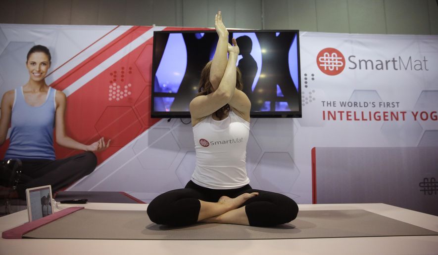 FILE - In this Jan. 7, 2015 file photo, a model exercises on the SmartMat, an intelligent yoga mat, at the SmartMat booth at the International CES in Las Vegas. SmartMat costs $297 and will ship in July. (AP Photo/Jae C. Hong)