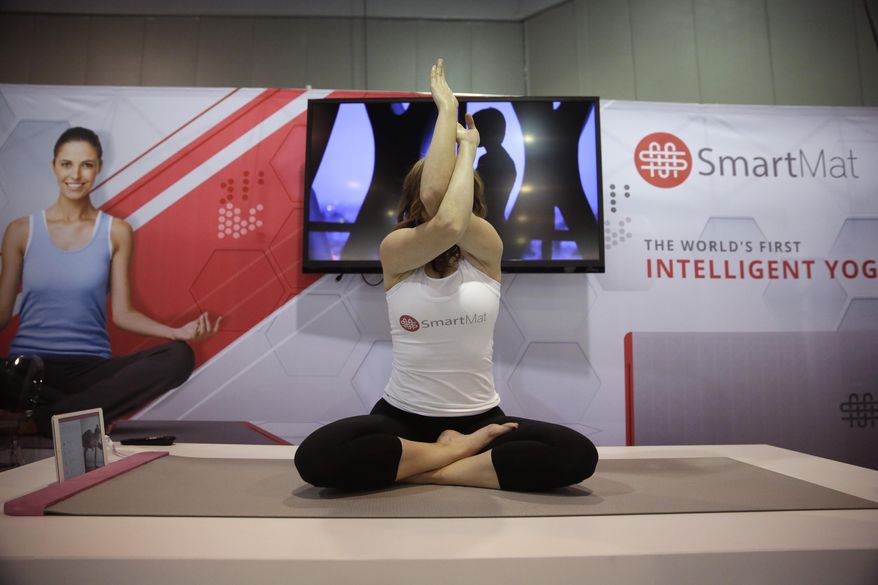 FILE - In this Jan. 7, 2015 file photo, a model exercises on the SmartMat, an intelligent yoga mat, at the SmartMat booth at the International CES in Las Vegas. SmartMat costs $297 and will ship in July. (AP Photo/Jae C. Hong)
