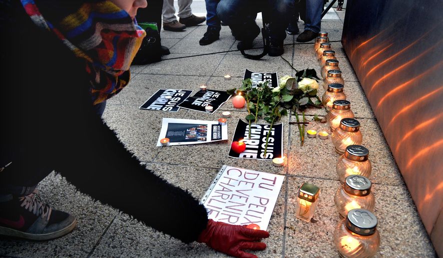 A woman puts a candle on the ground as she attends a ceremony to pay tribute to victims of the attack against the French satirical weekly Charlie Hebdo, in front of the French Institute in Budapest, Hungary, Thursday, Jan. 8, 2015, a day after 12 people were slain by two armed men who stormed the Paris offices of the magazine. (AP Photo/MTI, Zoltan Mathe) 
