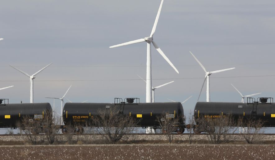 In this photo made Monday, Dec. 22, 2014, oil tankers train cars ride past windmills neat Sweetwater, Texas. Sweetwater is bracing for layoffs and budget cuts, anxious as oil prices fall and its largest investors pull back. (AP Photo/LM Otero)
