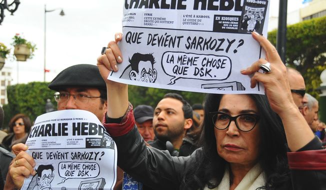 Tunisians hold up old copies of Charlie Hebdo on the iconic Bourguiba Avenue in Tunis, Tunisia, during a gathering in solidarity with those killed in an attack at the Paris offices of the weekly newspaper Charlie Hebdo, Friday, Jan. 9, 2015. Two sets of attackers seized hostages and locked down hundreds of French security forces around the capital on Friday, sending the city into fear and turmoil for a third day in a series of linked attacks that began with the deadly newspaper terror attack that left 12 people dead. (AP Photo/Hassene Dridi)