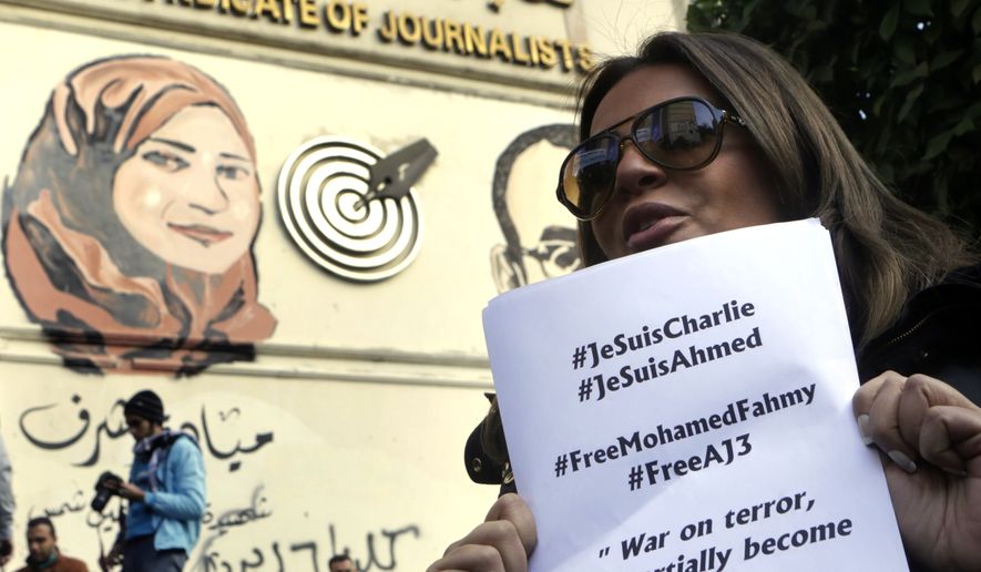 Marwa Omara, the fianc&amp;#233;e of jailed Al-Jazeera English journalist Egyptian-Canadian Mohammed Fahmy, holds a paper that quotes him and calls for his freedom from an Egyptian jail, as she participates in a show of solidarity with the victims of Wednesday&#39;s attack in Paris on the Charlie Hebdo newspaper, at the Press Syndicate in Cairo, Egypt, Sunday, Jan. 11, 2015. (AP Photo/Amr Nabil)