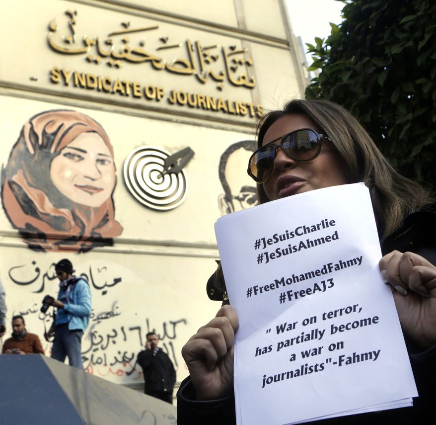 Marwa Omara, the fianc&amp;#233;e of jailed Al-Jazeera English journalist Egyptian-Canadian Mohammed Fahmy, holds a paper that quotes him and calls for his freedom from an Egyptian jail, as she participates in a show of solidarity with the victims of Wednesday&#39;s attack in Paris on the Charlie Hebdo newspaper, at the Press Syndicate in Cairo, Egypt, Sunday, Jan. 11, 2015. (AP Photo/Amr Nabil)