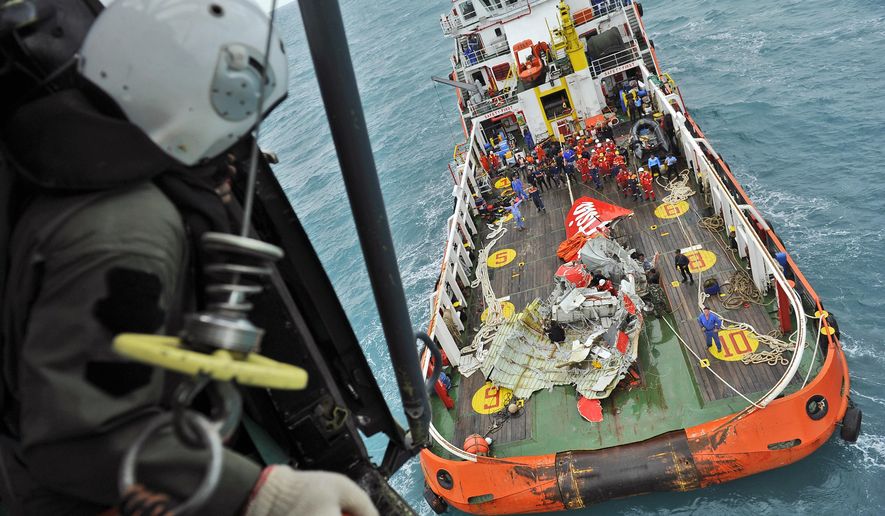 In this photo taken from an Indonesian Air Force Super Puma helicopter Saturday, Jan. 10, 2015, portion of the tail of AirAsia Flight 8501 is seen on the deck of a rescue ship after it was recovered from the sea floor on the Java Sea. Investigators searching for the crashed AirAsia plane's black boxes lifted the tail portion of the jet out of the Java Sea on Saturday, two weeks after it went down, killing all 162 people on board. (AP Photo/Prasetyo Utomo, Pool)