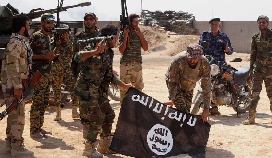 In this Tuesday, Oct. 7, 2014, file photo, Iraqi security forces hold a flag of the Islamic State group they captured during an operation outside Amirli, some 105 miles (170 kilometers) north of Baghdad, Iraq. (AP Photo, File) ** FILE **