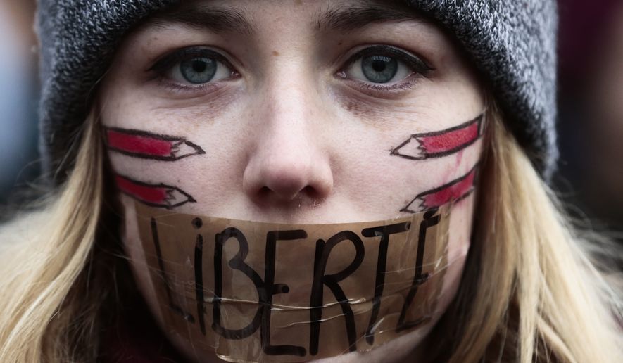 FILE &amp;#8211; In this Sunday, Jan. 11, 2015, file photo, a woman with her mouth taped displaying the word Freedom, gathers with several thousand people in Berlin to honor the 17 victims who died during three days of bloodshed in Paris last week, and to support freedom of expression. (AP Photo/Markus Schreiber, File)
