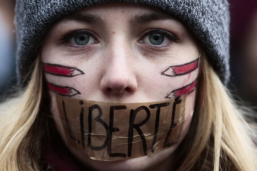FILE &amp;#8211; In this Sunday, Jan. 11, 2015, file photo, a woman with her mouth taped displaying the word Freedom, gathers with several thousand people in Berlin to honor the 17 victims who died during three days of bloodshed in Paris last week, and to support freedom of expression. (AP Photo/Markus Schreiber, File)