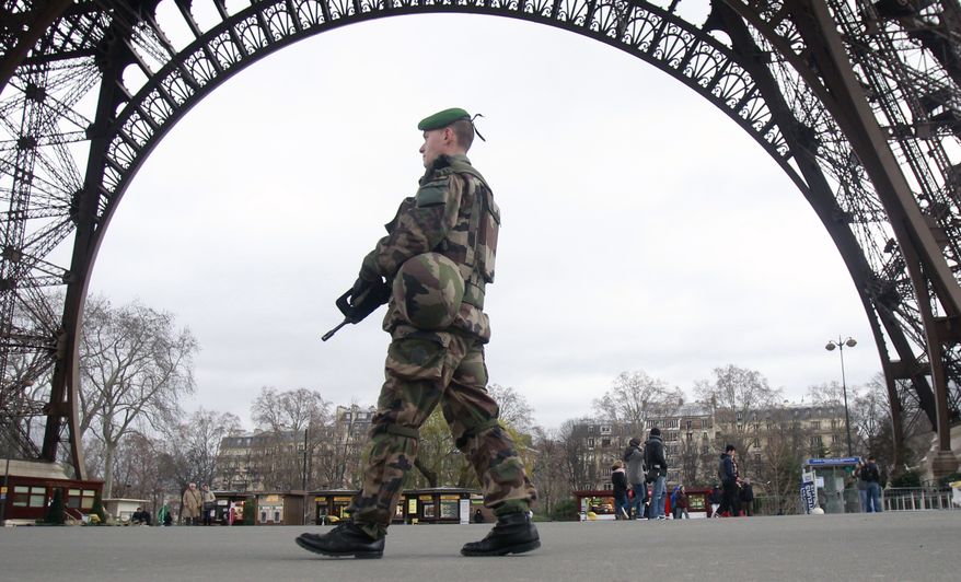 A French army soldier patrols under the Eiffel Tower in Paris, Tuesday Jan. 13, 2015. France on Monday ordered 10,000 troops into the streets to protect sensitive sites after three days of bloodshed and terror, amid the hunt for accomplices to the attacks that left 17 people and the three gunmen dead. (AP Photo/Remy de la Mauviniere)