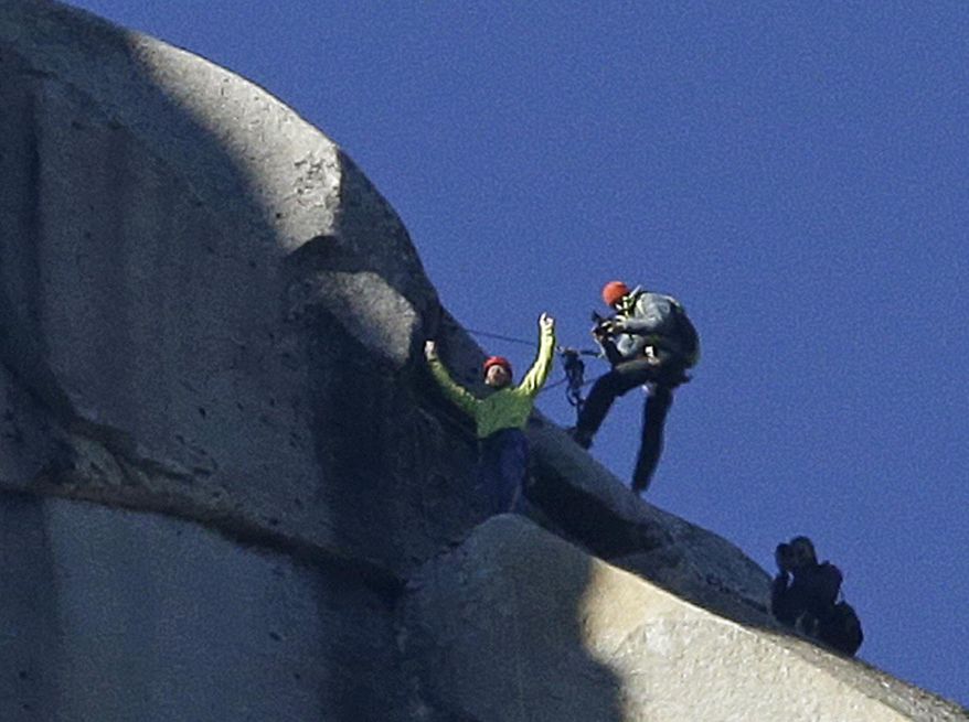 Tommy Caldwell, top, raises his arms after reaching the summit of El Capitan, Wednesday, Jan. 14, 2015, as seen from the valley floor in Yosemite National Park, Calif. Caldwell and Kevin Jorgeson became the first to free-climb the rock formation's Dawn Wall. They used ropes and safety harnesses to catch them in case of a fall, but relied entirely on their own strength and dexterity to ascend by grasping cracks as thin as razor blades and as small as dimes. (AP Photo/Ben Margot)