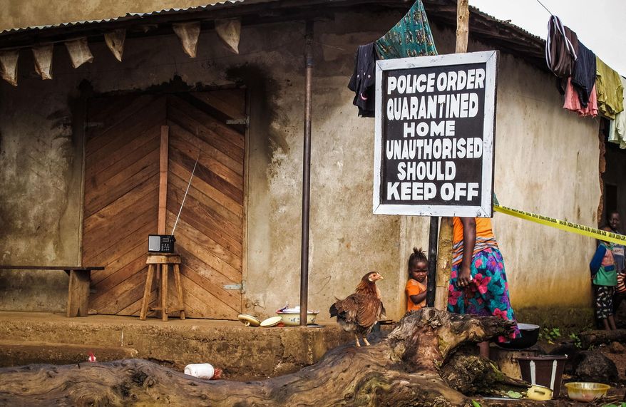 FILE-In this file photo taken on Wednesday, Oct. 22, 2014, A child, center, stands underneath a signboard as a family home is placed under quarantine due to the Ebola virus in Port Loko, Sierra Leone. Evan as his country registered 19 new Ebola cases over a 24-hour period, Sierra Leone’s president is predicting there will be zero new confirmed cases by the end of March, 2015. President Ernest Bai Koroma also predicted that his West African country _ one of three hardest hit by the outbreak _ would be Ebola-free by World Health Organization standards by May, 2015. (AP Photo/Michael Duff, File)