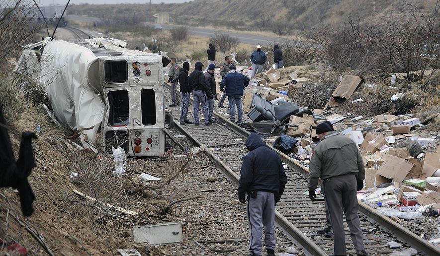 Authorities investigate the scene of a prison bus crash, Wednesday, Jan. 14, 2015, in Penwell, Texas. Law enforcement officials said the bus, carrying prisoners and corrections officers, fell from an overpass in West Texas and collided with a passing freight train, killing at least 10 people. (AP Photo/Odessa American, Mark Sterkel)