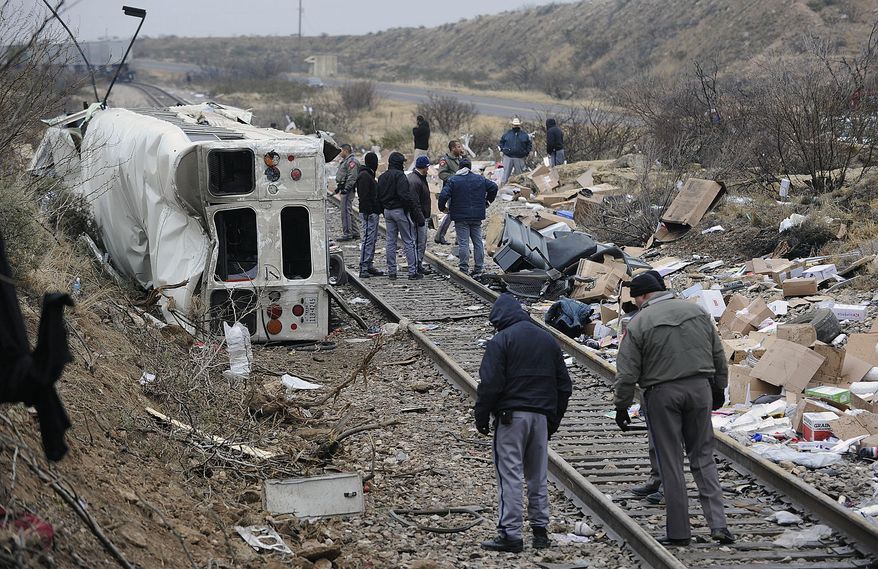 Authorities investigate the scene of a prison bus crash, Wednesday, Jan. 14, 2015, in Penwell, Texas. Law enforcement officials said the bus, carrying prisoners and corrections officers, fell from an overpass in West Texas and collided with a passing freight train, killing at least 10 people. (AP Photo/Odessa American, Mark Sterkel)