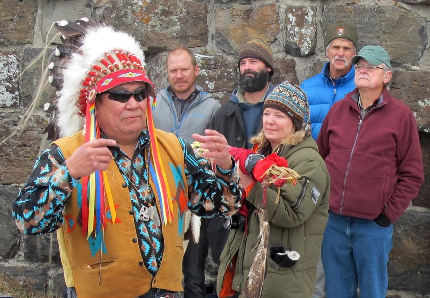 In a Monday, Jan. 12 2015 photo, Jimmy St. Goddard, left, a spiritual chief for the Blackfeet Tribe, talks as individuals involved in wolf reintroduction and management listen behind him, at Roosevelt Arch near Gardiner, Mt. It was 1995 when the first eight wolves live-trapped in Canada were placed inside fenced enclosures in Yellowstone to acclimate them to the area in hopes they would not immediately bolt back to their homeland. Twenty years later, about 130 wolves in 11 packs inhabit Yellowstone. From left to right are Dan Stahler, Yellowstone biologist; Nathan Varley, former field biologist volunteer; Doug Smith, Wolf Project biologist; and John Varley, former Yellowstone Resource Center chief.(AP Photo/The Billings Gazette, Brett French)
