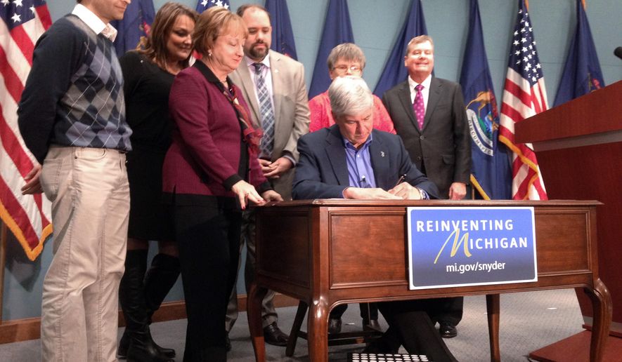 Gov. Rick Snyder signs “Main Street fairness” laws Thursday, Jan. 15, 2015 in Lansing, Mich., to ensure roughly $60 million a year in taxes on out-of-state purchases are collected. Michigan residents who buy from Amazon, Overstock and some other online retailers will be forced to pay the state’s 6 percent sales tax starting in October, a move to close what backers say is a loophole that has left traditional businesses at a disadvantage. (AP Photo/David Eggert)