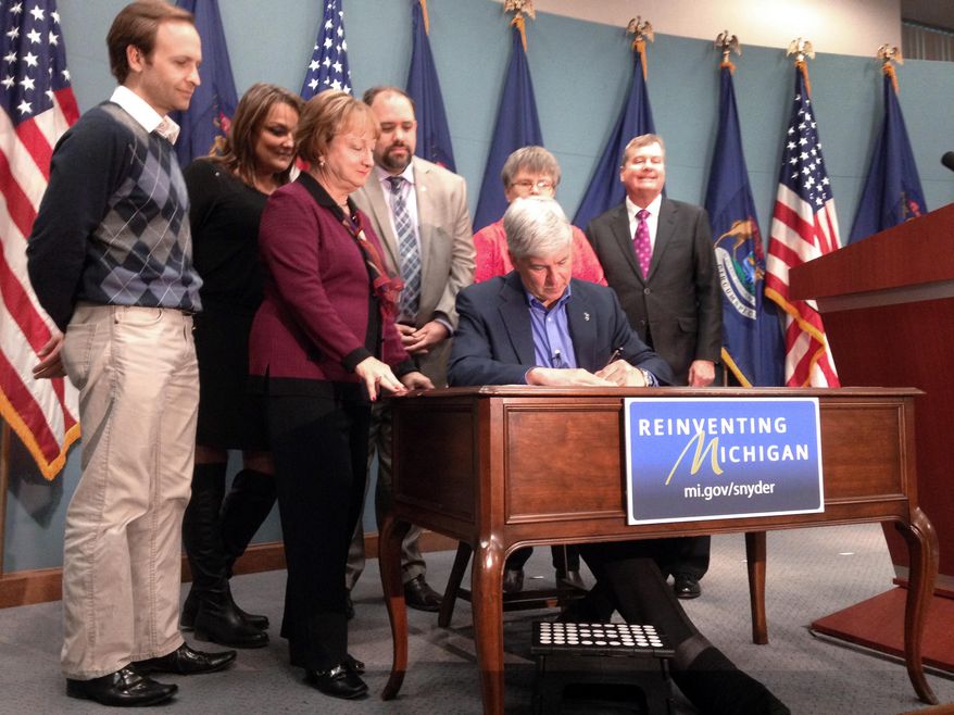 Gov. Rick Snyder signs “Main Street fairness” laws Thursday, Jan. 15, 2015 in Lansing, Mich., to ensure roughly $60 million a year in taxes on out-of-state purchases are collected. Michigan residents who buy from Amazon, Overstock and some other online retailers will be forced to pay the state’s 6 percent sales tax starting in October, a move to close what backers say is a loophole that has left traditional businesses at a disadvantage. (AP Photo/David Eggert)